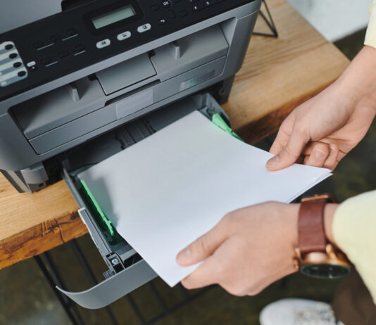 Toner printer of werken met cartridges? Maak de juiste keuze voor jouw bedrijf! Man plaatst papier in printer