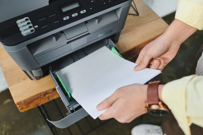 Man plaatst papier in printer